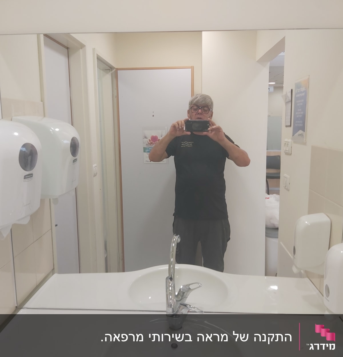 מראה גדולה מעל כיור בחדר רחצה